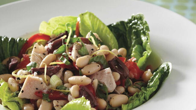 White Bean and Tuna Salad with red pepper and scallions on a bed of lettuce in a white bowl